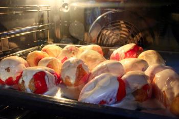 stuffed paprika covered by sour cream sauce cooking in the oven