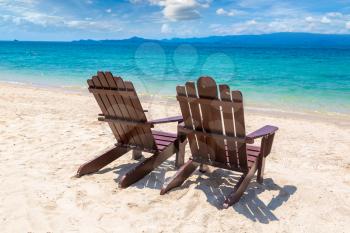 Empty wooden chairs on a sandy beach on Koh Samui island, Thailand in a summer day