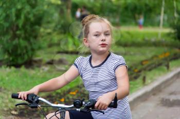 Photo of cute girl driving bicycle in summer