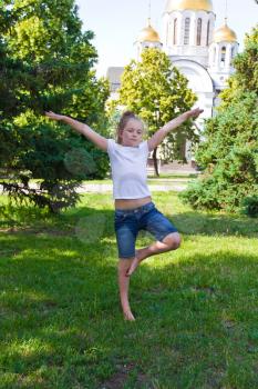 Cute girl with blond hair jumping on one leg