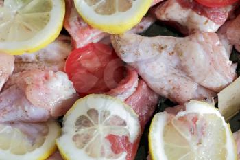 Raw chicken wings with lemon and tomato
