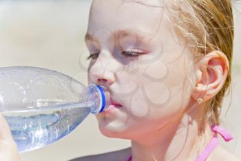 Cute blond girl with drinking water from bottle