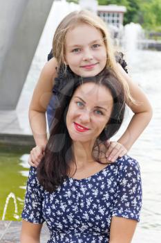 Embracing brunette mother and blond daughter with long hairs