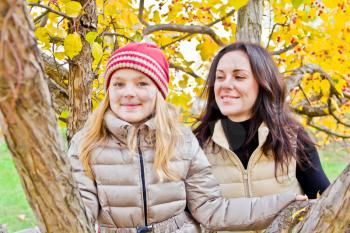 Photo of mother and daughter in autumn sitting on tree