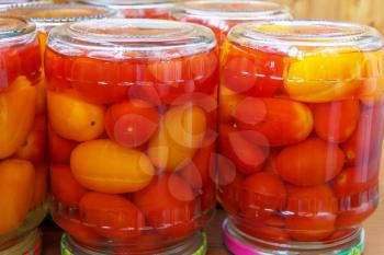 Red and yellow tomatoes in glass jar on the kitchen table