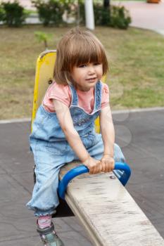 Sad baby riding on hutches at the playground with disheveled hair