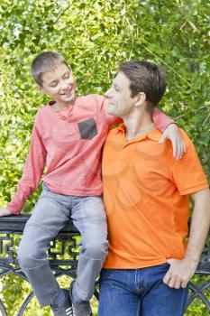 Father and son are talking smiling in summer park