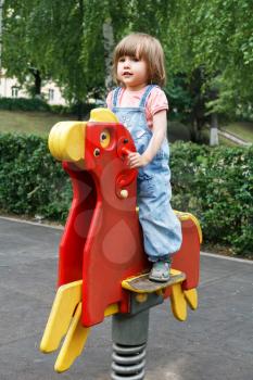 Baby riding on hutches at the playground with disheveled hair