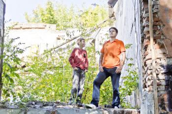 Father and teenager son are standing in ruins