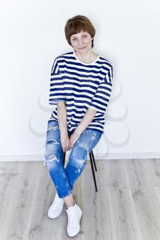 Beautiful woman with haitcut near white wall in striped clothes
