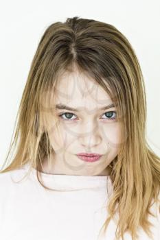 Cute angry girl with blond long hair on white wall in pink clothes