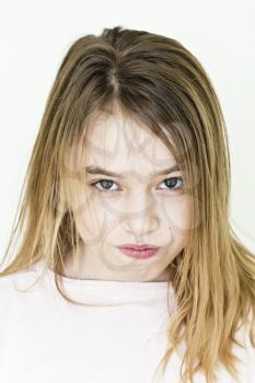 Cute angry girl with blond long hair on white wall in pink clothes