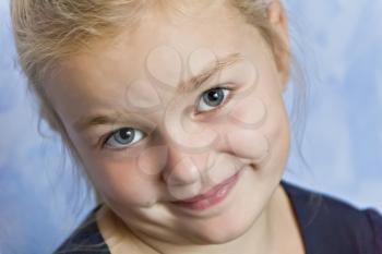 Cute smiling girl with blond hair on blue background