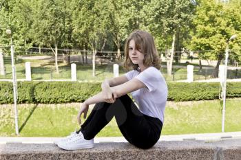 Girl fourteen years old in white are sitting on the curb