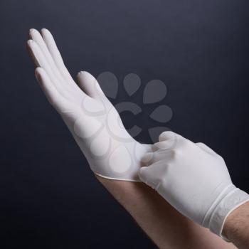 Male hands putting on latex gloves on dark background