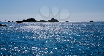 rocks in sea and patch of sunlight in the water