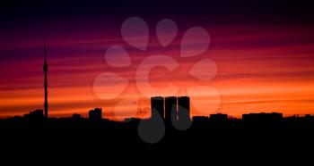 silhouettes of buildings and TV tower at red sunset's light