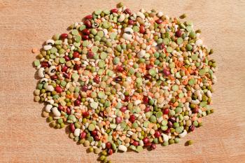 mix of different dry beans for Italian lentil soup on wooden board in summer day