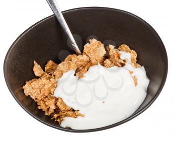 yoghurt and spoon into bowl of cereal isolated on white background