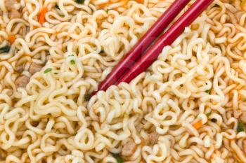 eating of cooked instant noodles by red chopsticks close up
