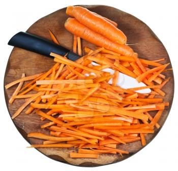 top view of wooden cutting board with raw strips sliced carrot and ceramic knife isolated on white background