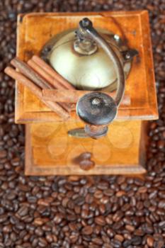 top view of retro manual coffee grinder on many roasted coffee beans and cinnamon bark