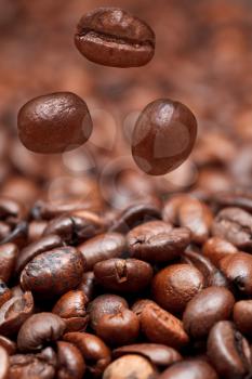 falling beans and dark roasted coffee beans background with focus foreground