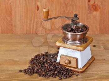 heap of coffee and retro manual coffee mill on wooden table