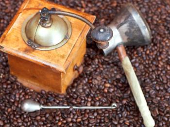 above view of retro manual coffee grinder and copper pot on many roasted coffee beans