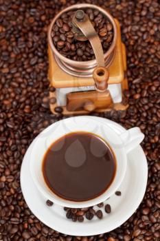 top view cup of coffee and roasted coffee beans with retro manual copper mill