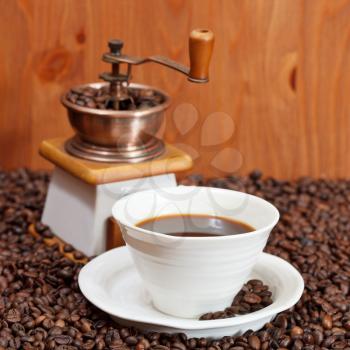 cup of coffee and roasted coffee beans with retro manual grinder