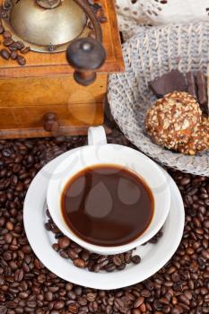 above view cup of coffee and roasted coffee beans with retro wooden manual mill, biscuit, openwork napkin