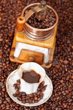 above view small cup of coffee and roasted coffee beans with retro copper manual mill