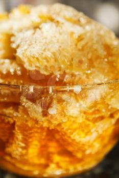 fresh honey in comb in glass bowl at table close up