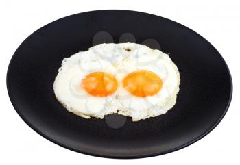 fried eggs on ceramic black plate isolated on white background
