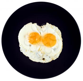 top view of two fried eggs on ceramic black plate isolated on white background