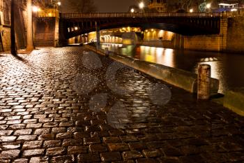 cobblestone paved quay in Paris at night