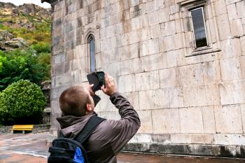 tourist shooting landmark by smartphone - Katoghiken church of medieval geghard monastery in Armenia