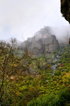 Cliffs in fog cloud in rain in Armenia. Cliffs surrounding Geghard monastery and Azat river gorge are included together with the monastery in the World Heritage Site listing.