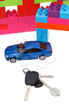 door and car keys close up, blue model car and plastic block house isolated on white background