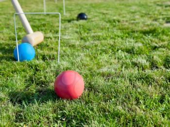 mallet and balls in game of croquet on green lawn in summer day