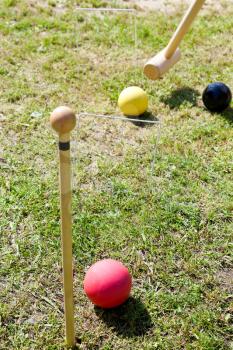 hitting of yellow ball in game of croquet on green lawn in summer day
