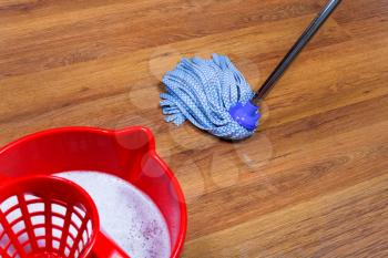 red bucket with water and mopping of laminate floors