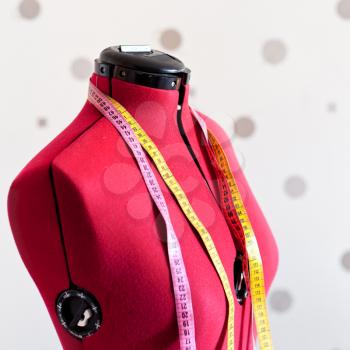 red tailors mannequin with two measure tapes