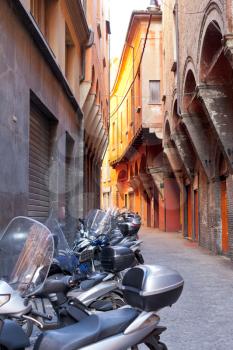 motorbike parking on Bologna old narrow street in morning, Italy