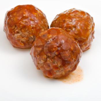 three roasted meatballs under meat sauce on white plate