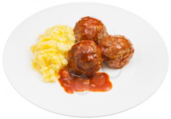 portion of roasted meatballs under meat sauce and mashed potato on plate isolated on white background