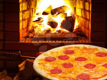 italian pizza with salami and open fire in wood burning oven