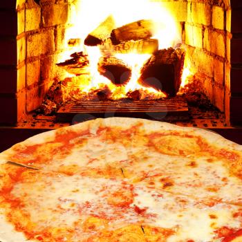 italian pizza margherita and open fire in wood burning stove
