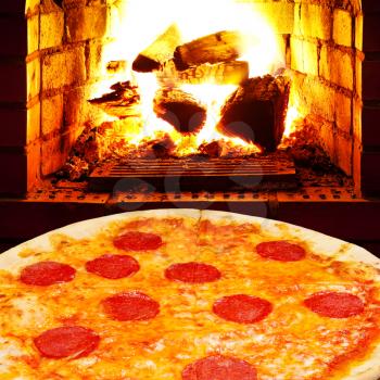 italian pizza with salami and open fire in wood burning stove